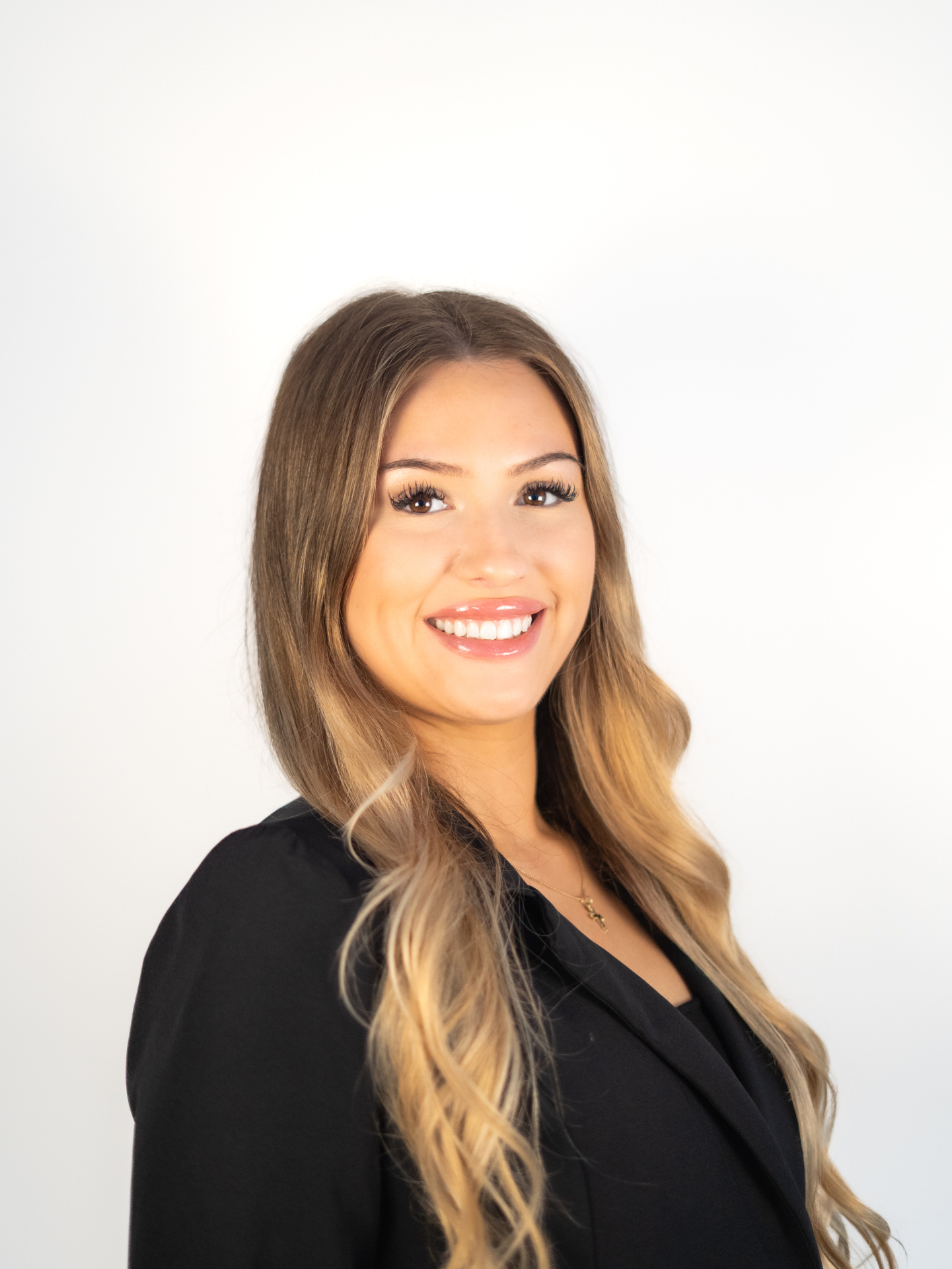 A professional headshot of a woman in a black blazer against a white background.